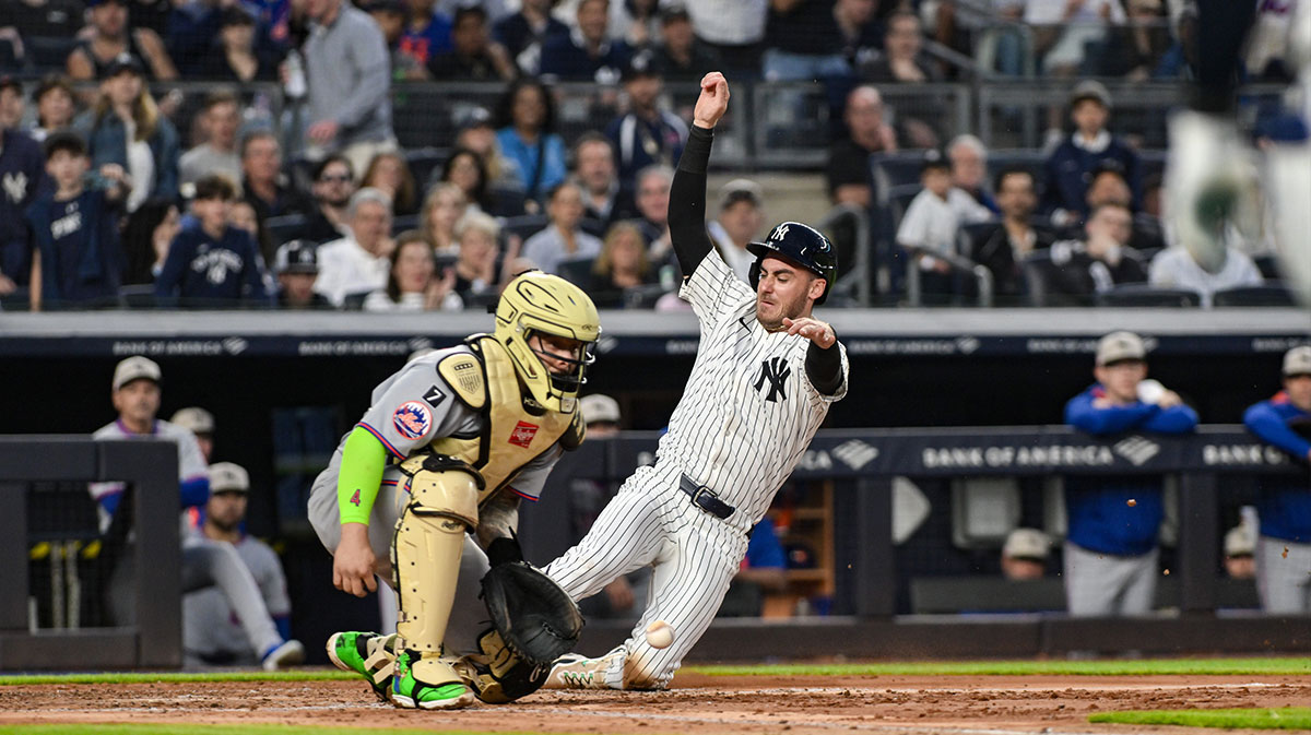 New York Yankees outfielder Cody Bellinger (35) scores ahead of the tag by New York Mets catcher Francisco Alvarez (4) on a sacrifice fly by shortstop Anthony Volpe (not pictured) during the third inning at Yankee Stadium.