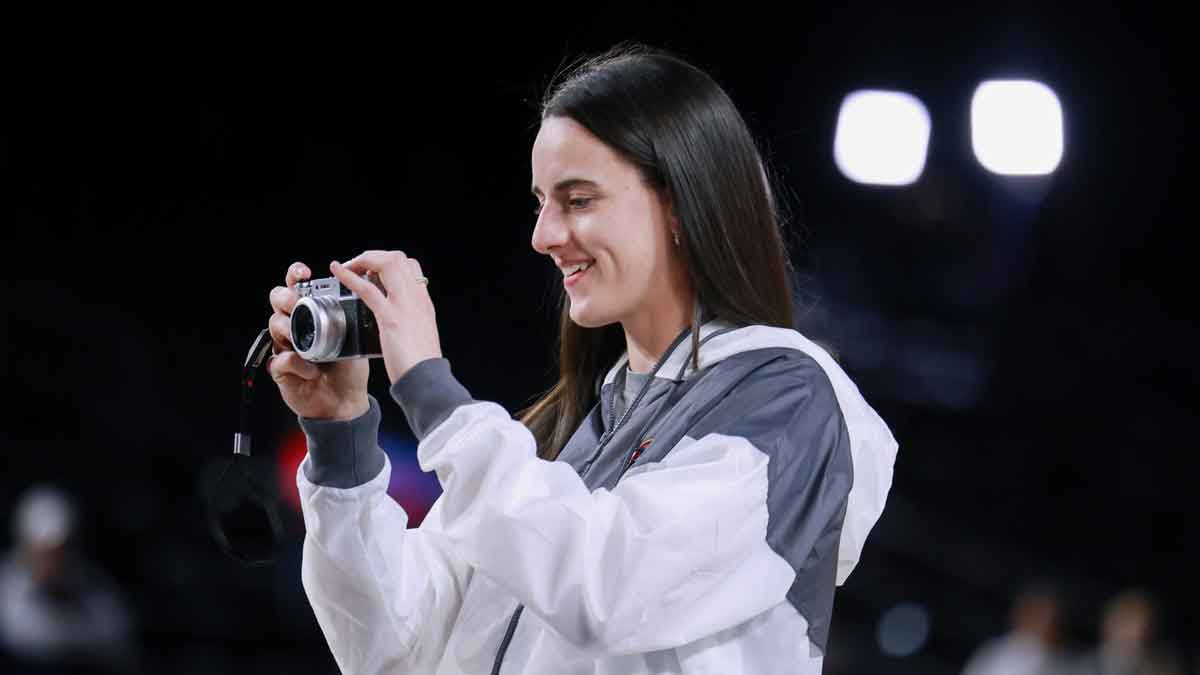 Indiana Fever guard Caitlin Clark (22) takes photos of her teammates warming up before the game against the Washington Mystics at Entertainment & Sports Arena.