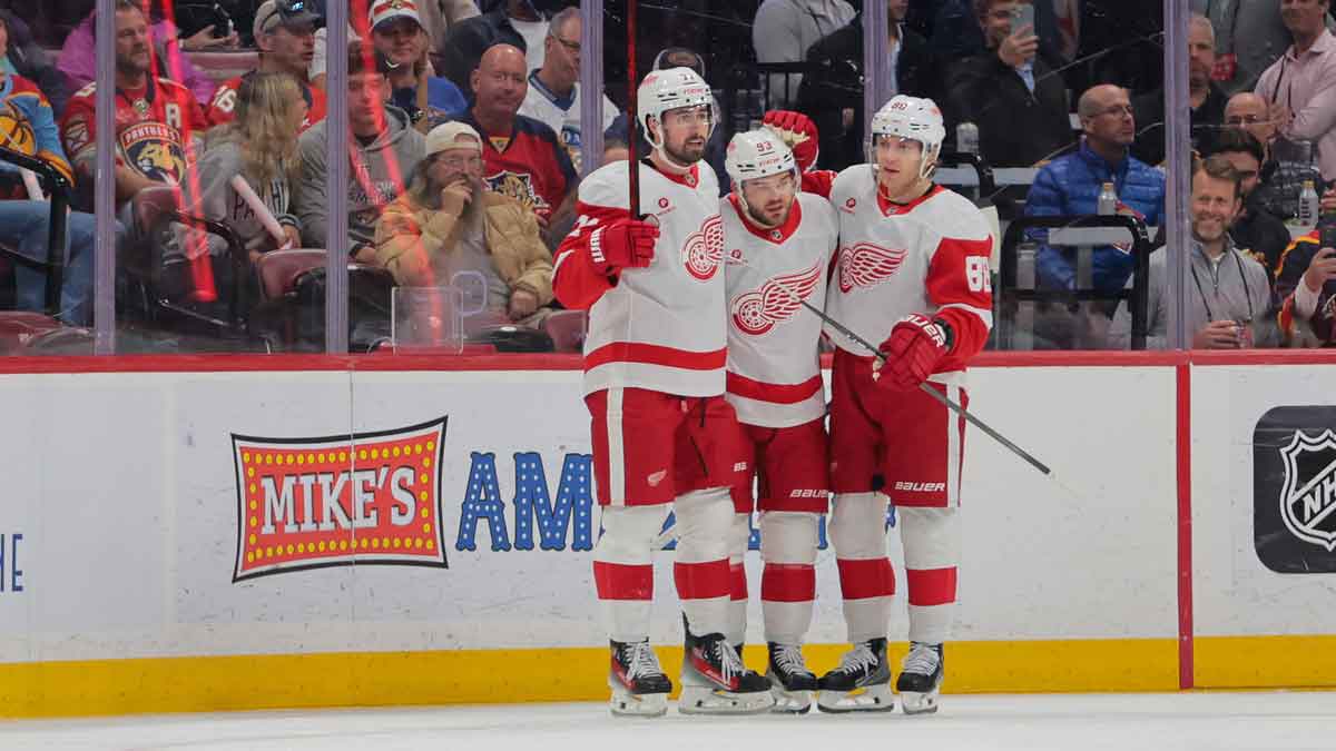 Detroit Red Wings right wing Alex DeBrincat (93) celebrates with center Dylan Larkin (71) and right wing Patrick Kane (88) after scoring against the Florida Panthers during the first period at Amerant Bank Arena.