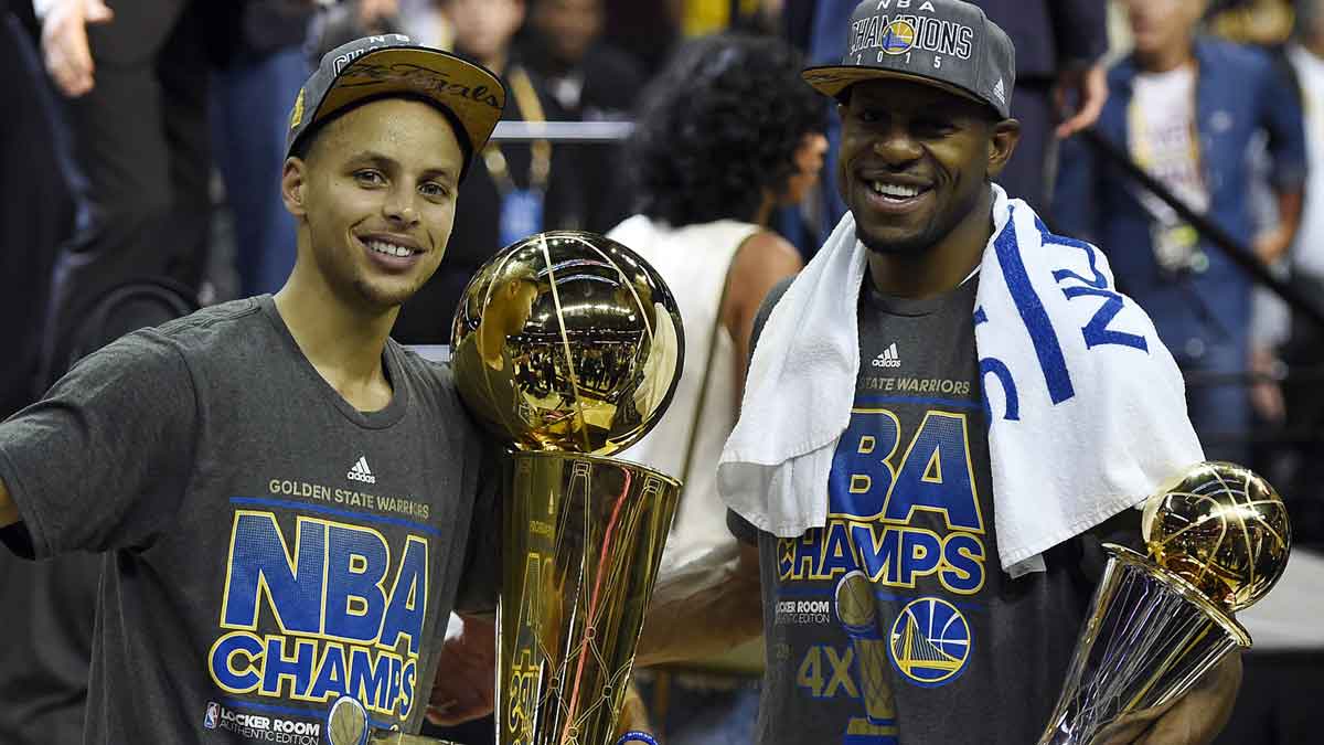 Golden State Warriors guard Stephen Curry (30) poses with the Larry O'Brien Trophy as Golden State Warriors guard Andre Iguodala (9) celebrates with the NBA Finals MVP trophy after beating the Cleveland Cavaliers in game six of the NBA Finals at Quicken Loans Arena.