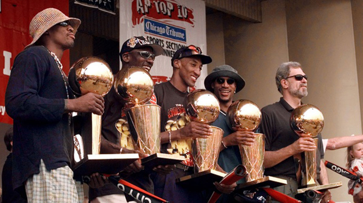 Chicago Bulls players, left to right, Ron Harper, Dennis Rodman, Scottie Pippen, Michael Jordan & coach Phil Jackson hold up the Bulls' five championship trophies at a rally in Grant Park.