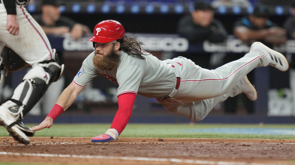 Jun 16, 2025; Miami, Florida, USA; Philadelphia Phillies center fielder Brandon Marsh (16) dives safely into home plate as Miami Marlins catcher Liam Hicks (34) looks on in the ninth inning at loanDepot Park. Mandatory Credit: Jim Rassol-Imagn Images