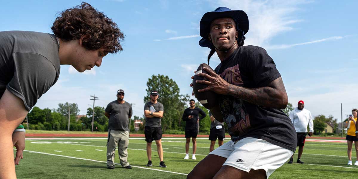 Josh Putman, 19, a member of Quarterback University, snaps the ball to Bryce Underwood, 17, a freshman quarterback at the University of Michigan, during a private workout