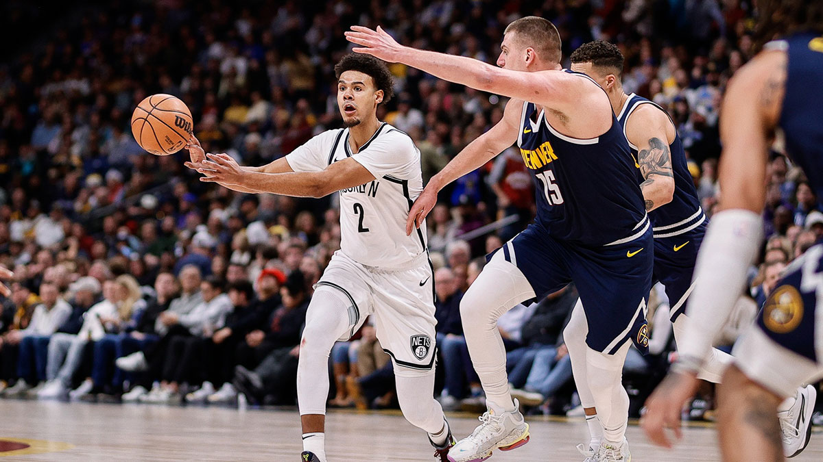 Brooklyn Nets forward Cam Johnson (2) passes the ball as Denver Nuggets center Nikola Jokic (15) guards in the second quarter at Ball Arena.