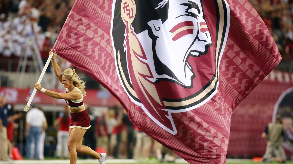 Florida State Seminoles cheerleader carries a Seminoles flag on the field before the game against the Oklahoma State Cowboys at AT&T Stadium. Aug 30, 2014; Arlington, TX, USA; Florida State beat Oklahoma State 37-31.