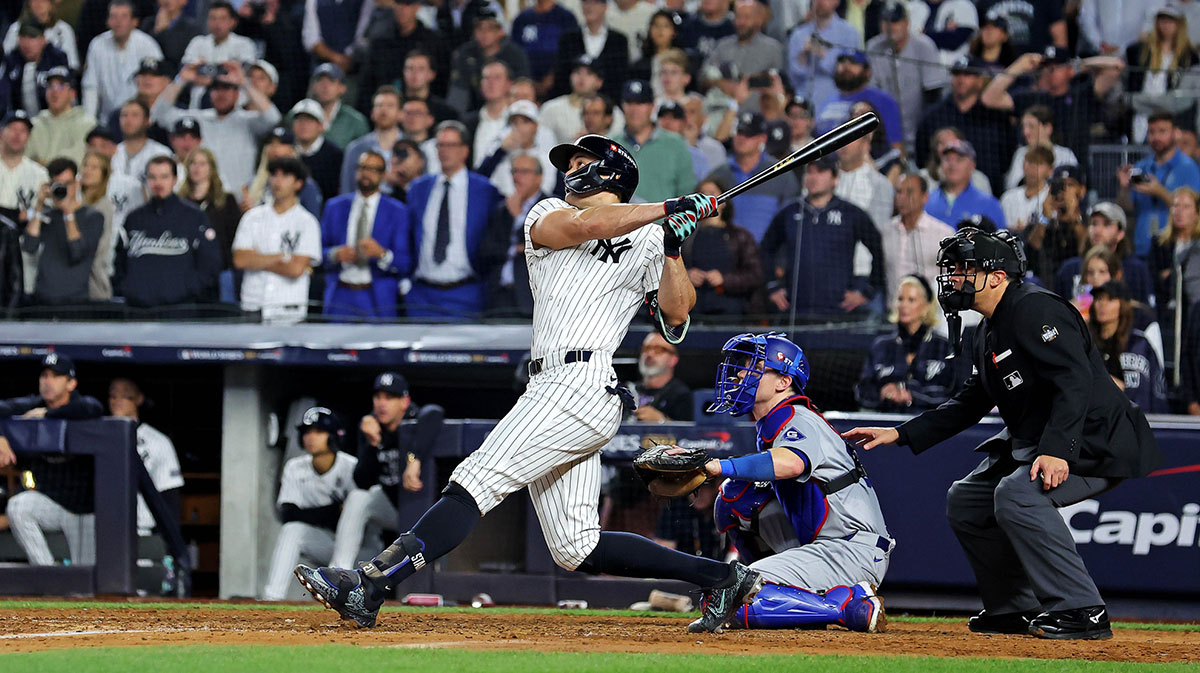 Oct 30, 2024; New York, New York, USA; New York Yankees designated hitter Giancarlo Stanton (27) hits an RBI sacrifice fly during the sixth inning against the Los Angeles Dodgers in game four of the 2024 MLB World Series at Yankee Stadium.