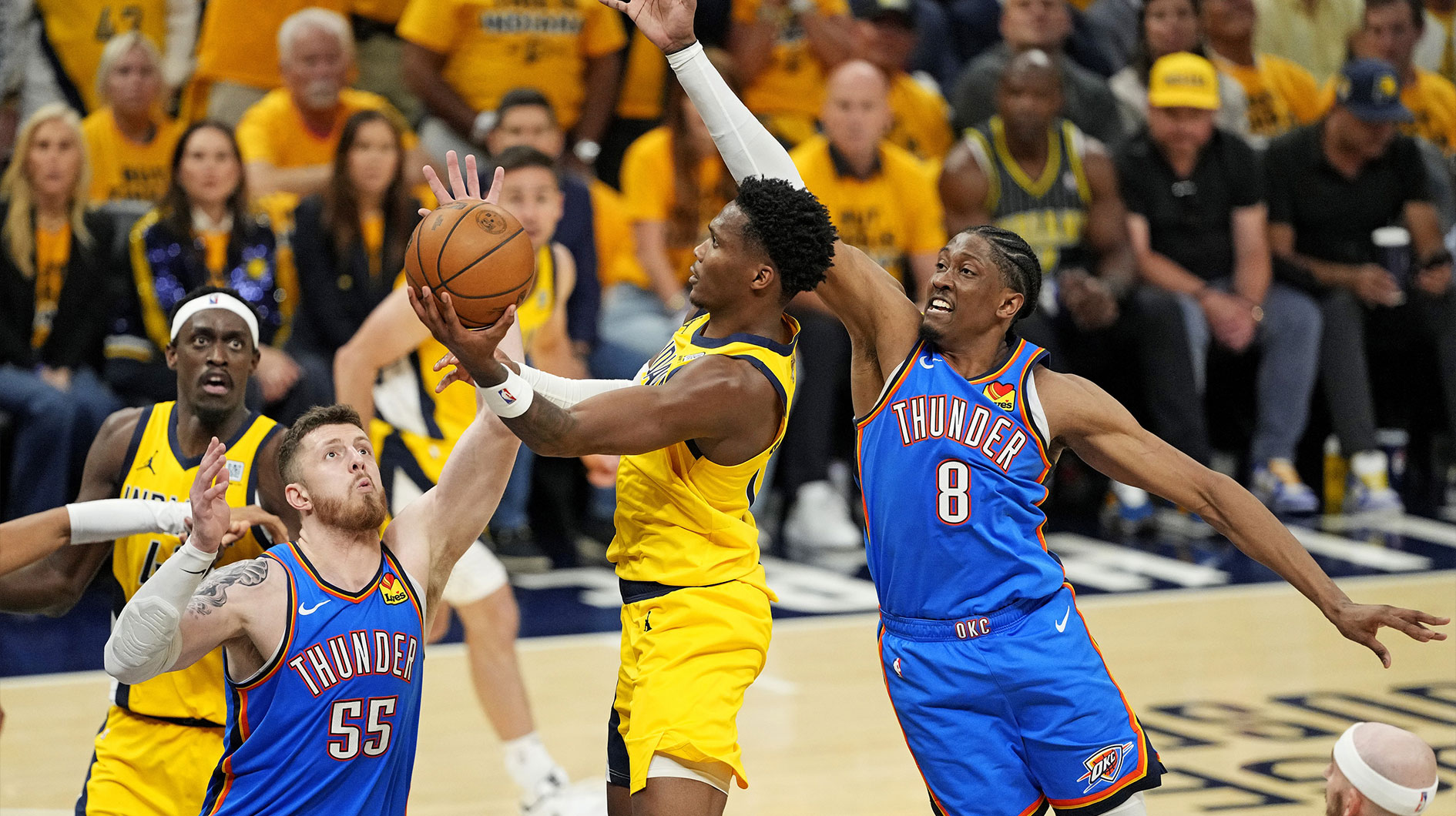 Indiana Pacers guard Bennedict Mathurin (00) shoots the ball against Oklahoma City Thunder center Isaiah Hartenstein (55) and forward Jalen Williams (8) during the fourth quarter in game three of the 2025 NBA Finals at Gainbridge Fieldhouse.