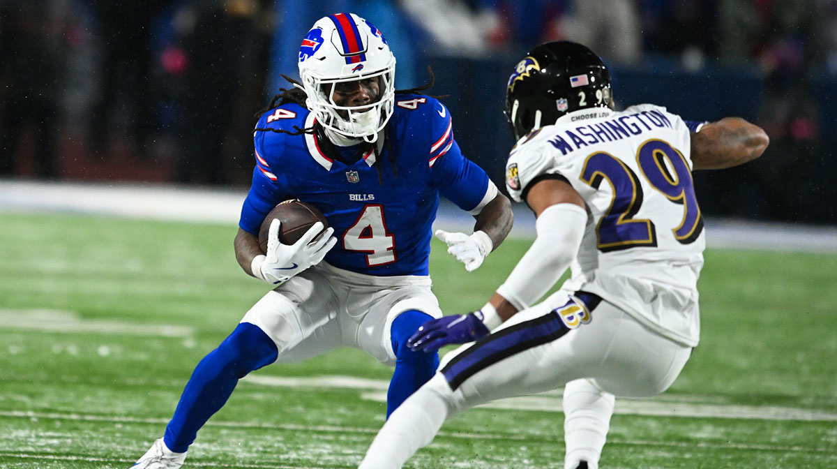 Buffalo Bills running back James Cook (4) runs the ball against Baltimore Ravens safety Ar'Darius Washington (29) during the fourth quarter in a 2025 AFC divisional round game at Highmark Stadium.