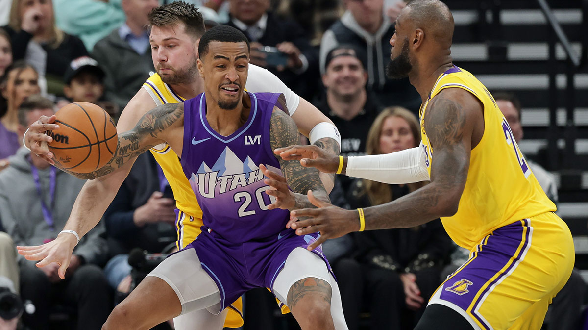 Utah Jazz forward John Collins (20) tries to keep the ball away from Los Angeles Lakers guard Luka Doncic (77) and forward LeBron James (23) during the first quarter at Delta Center.