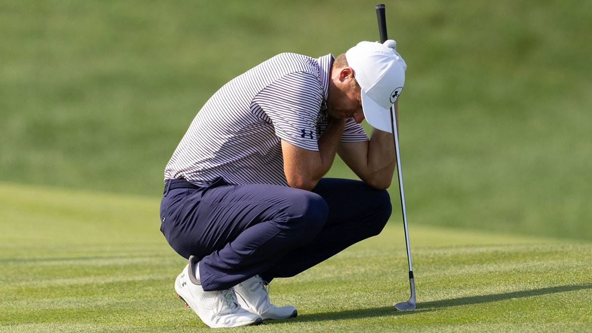 Jordan Spieth crouches while grabbing his upper body on the 12th hole during the first round of the Travelers Championship golf tournament