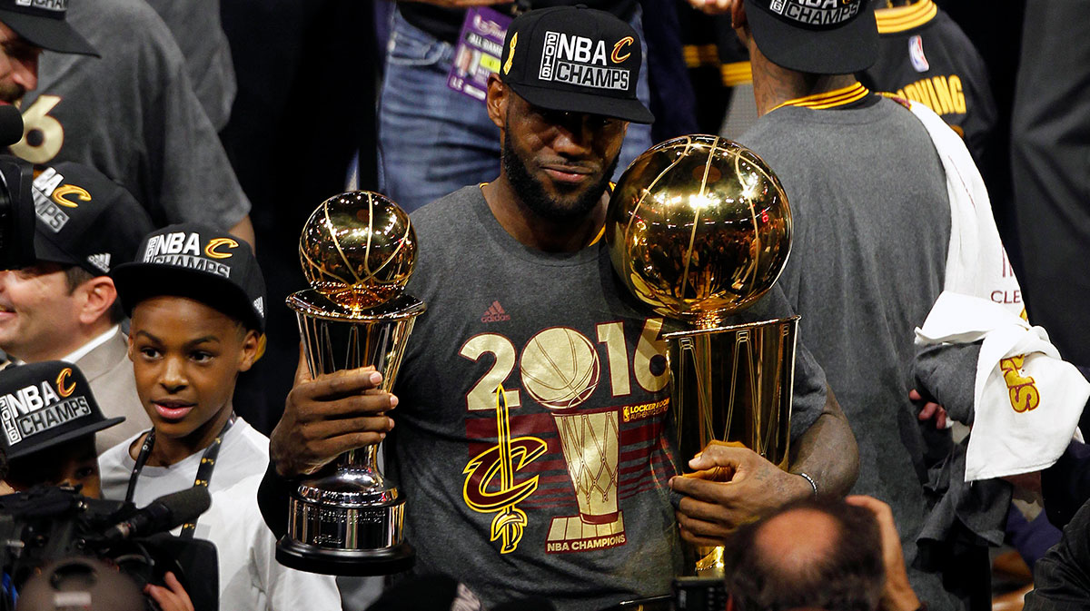 Cleveland Cavaliers forward LeBron James (23) celebrates with the Larry O'Brien championship and Bill Russell MVP trophies following the 93-89 victory against the Golden State Warriors in game seven of the NBA Finals at Oracle Arena.