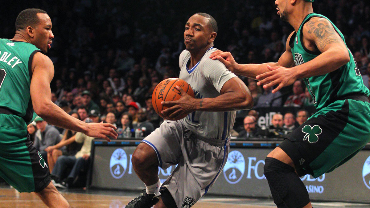 Brooklyn Nets point guard Marquis Teague (12) drives against Boston Celtics point guard Avery Bradley (0) and point guard Jerryd Bayless (11) during the fourth quarter of a game at Barclays Center.