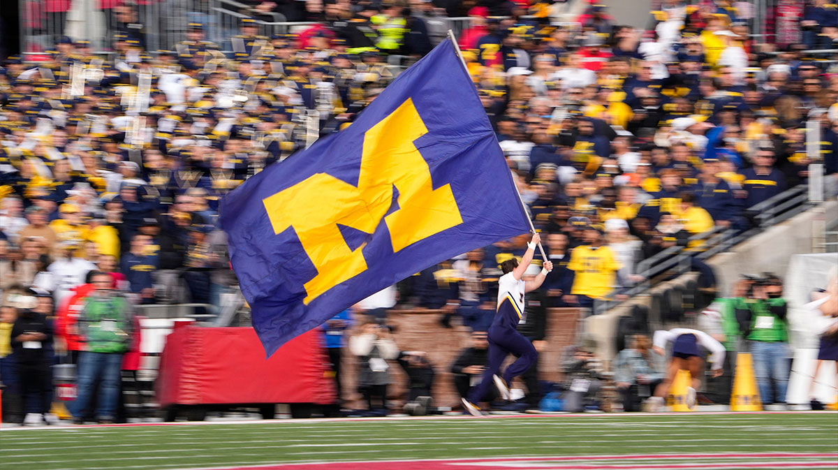 A Michigan Wolverines cheerleader runs with the M flag after a touchdown during the second half of the NCAA football game against the Ohio State Buckeyes at Ohio Stadium. Ohio State lost 45-23.