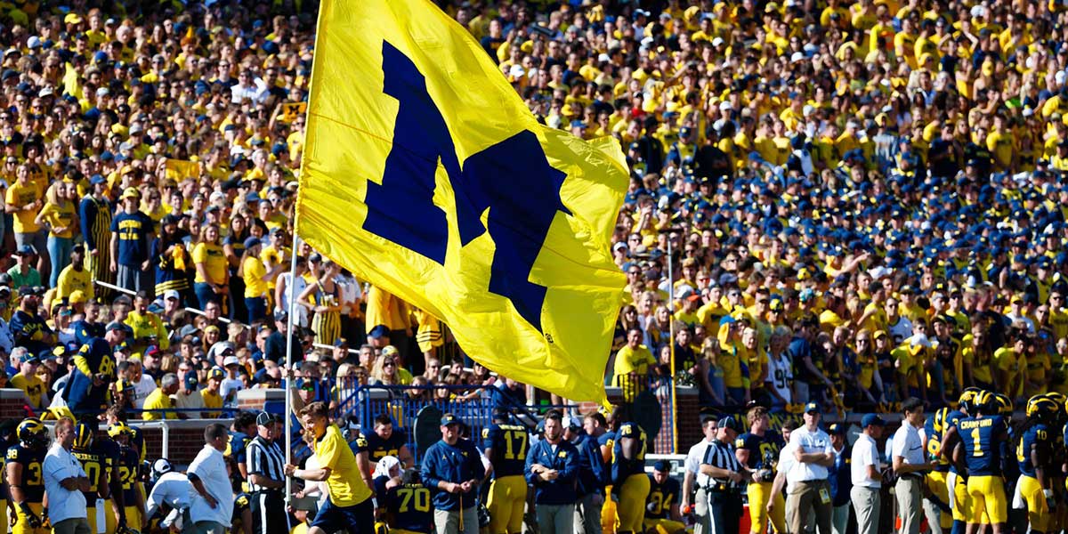 Michigan Wolverines cheerleader runs down the sideline with a flag after a touchdown in the first quarter against the Penn State Nittany Lions at Michigan Stadium.