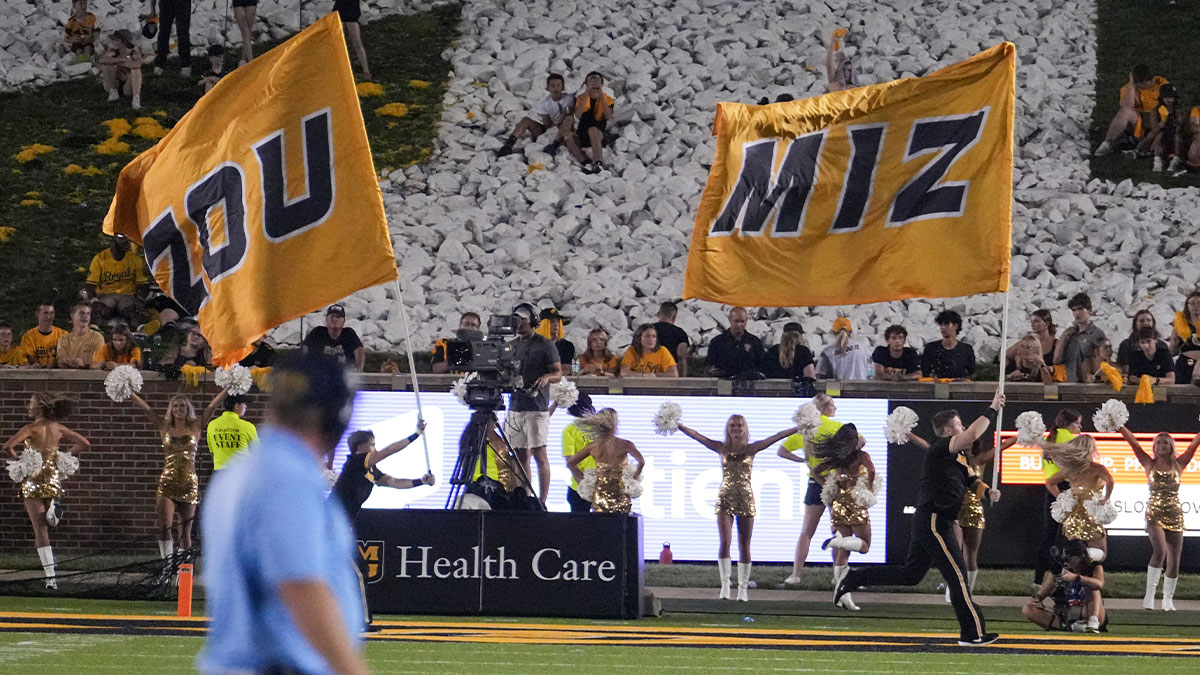 Missouri Tigers cheerleaders carry large flags as Murray State Racers head coach Jody Wright, foreground), leaves the field after the loss to the Tigers at Faurot Field at Memorial Stadium.