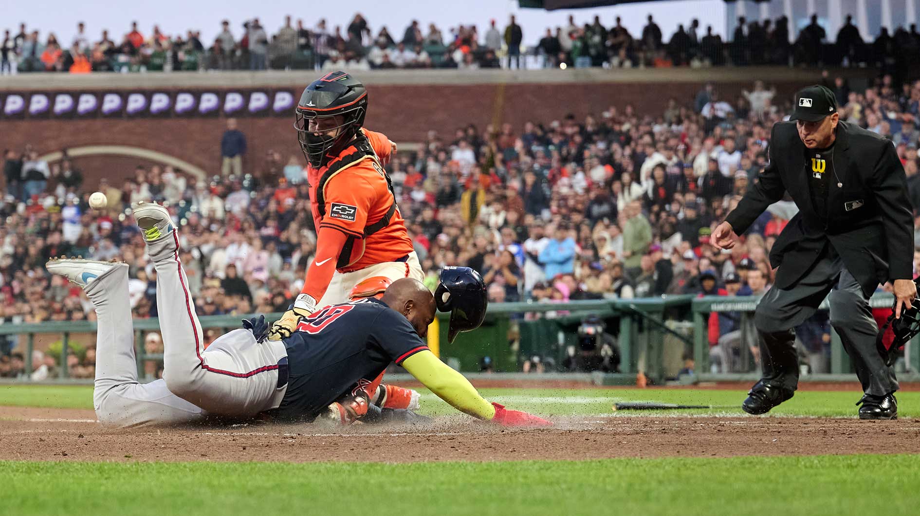Atlanta Braves designated hitter Marcell Ozuna Jr (20) slides safely into home against San Francisco Giants catcher Patrick Bailey (14) as umpire Andy Fletcher (49) watches the play during the fourth inning at Oracle Park.