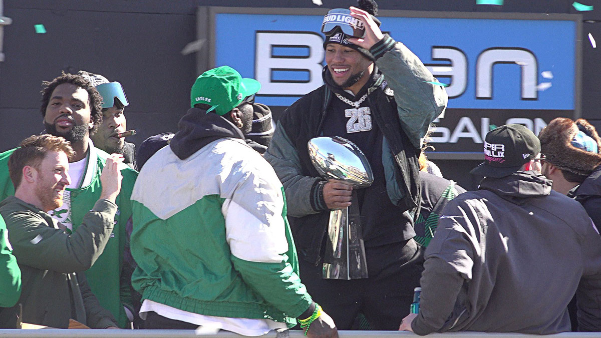 Eagles running back Saquon Barkley, center, holds the Vince Lombardi trophy during the Eagles Super Bowl championship parade on Friday, Feb. 14, 2025. 