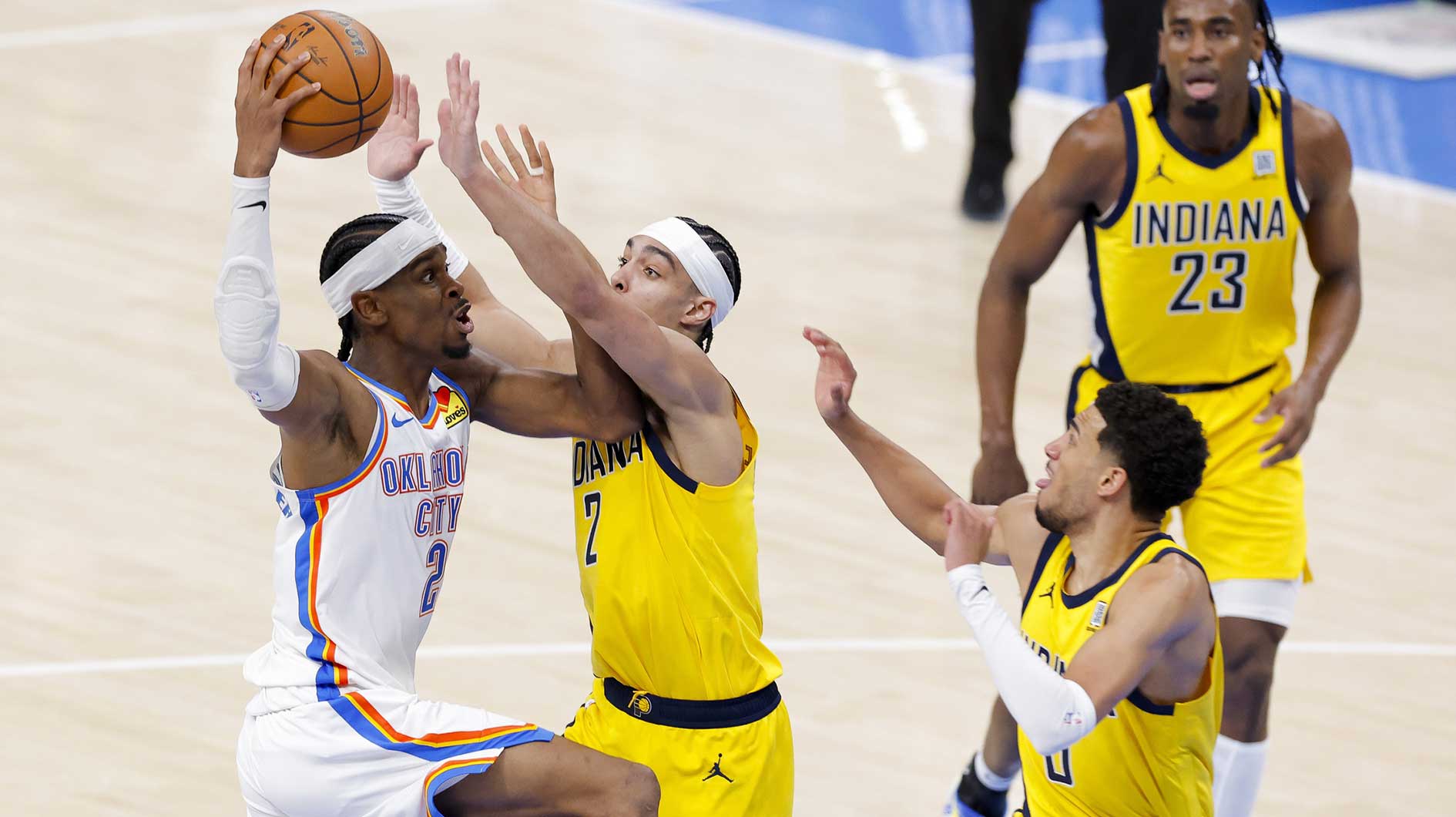 Oklahoma City Thunder guard Shai Gilgeous-Alexander (2) looks to pass the ball by Indiana Pacers guard Andrew Nembhard (2) and Indiana Pacers guard Tyrese Haliburton (0) during the fourth quarter during game one of the 2025 NBA Finals at Paycom Center.