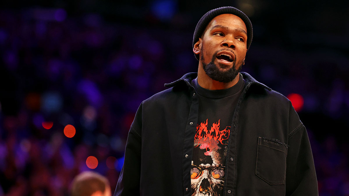 Kevin Durant looks on from the sidelines during the game between the Phoenix Suns and the New York Knicks at Footprint Center with ESPN's Brian Windhorst in the background