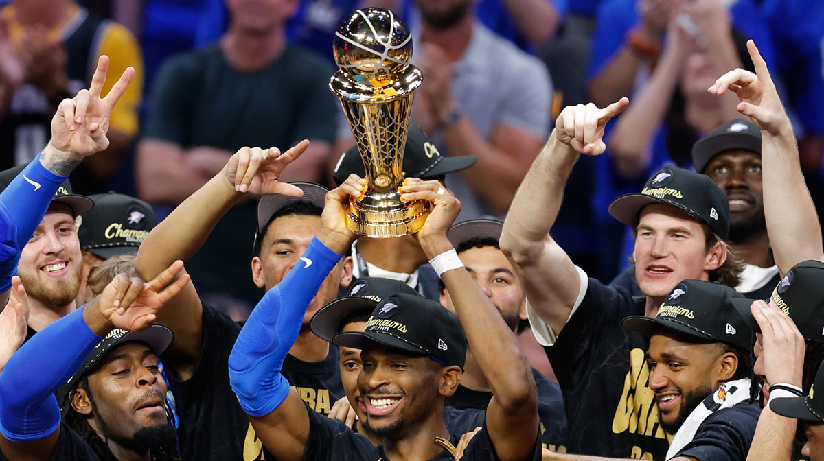 Thunder guard Shai Gilgeous-Alexander (2) lifts the Larry O'Brien Championship Trophy as the Oklahoma City Thunder celebrate after winning game seven of the 2025 NBA Finals against the Indiana Pacers at Paycom Center next to the Thunder front office