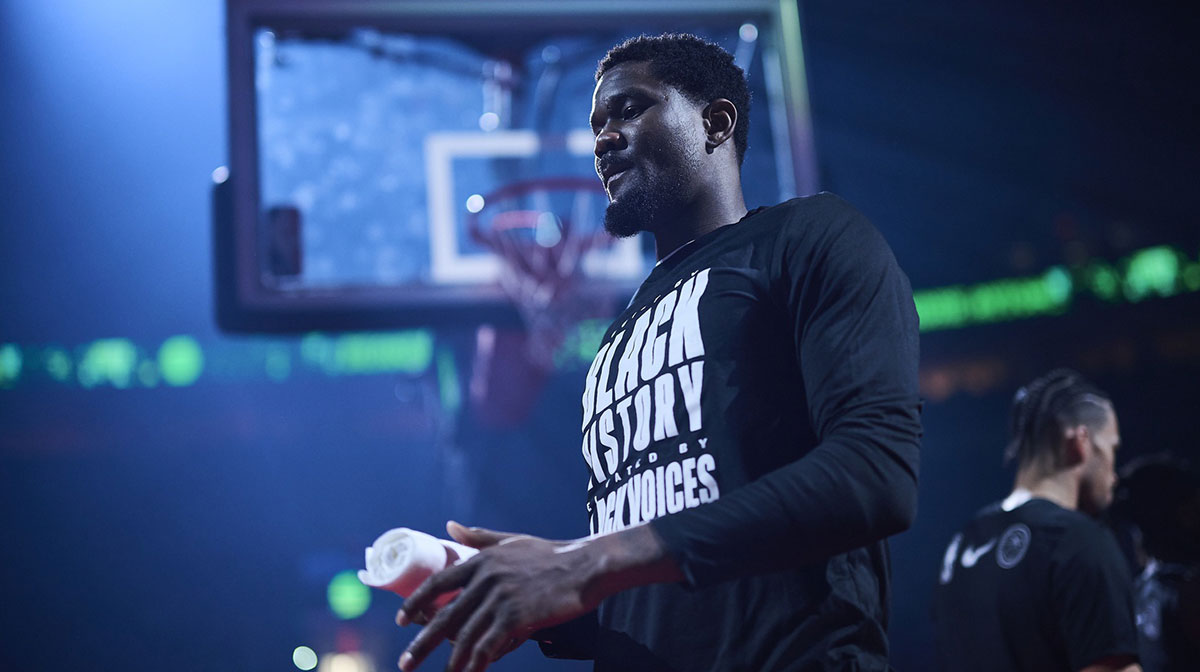 Trail Blazers center Deandre Ayton (2) walks out to the court during introductions before a game against the Sacramento Kings at Moda Center with ESPN's Kendrick Perkins in the background