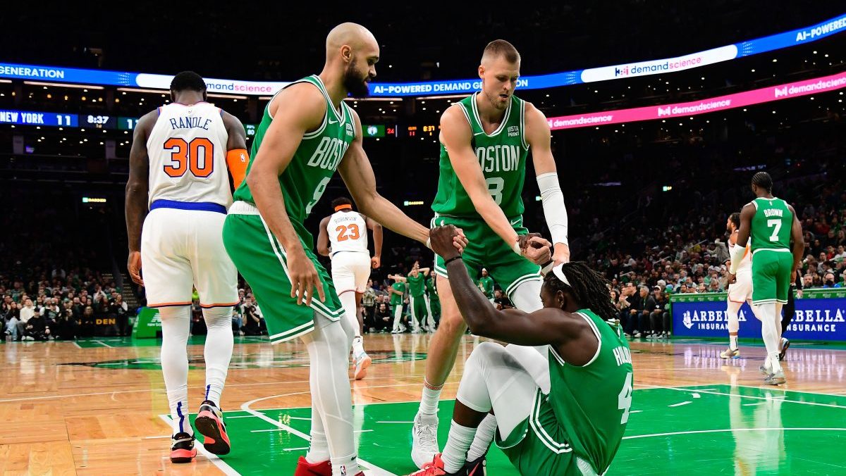 Boston Celtics guard Jrue Holiday (4) is helped to his feet by guard Derrick White (9) and center Kristaps Porzingis (8) during the first half against the New York Knicks at TD Garden.
