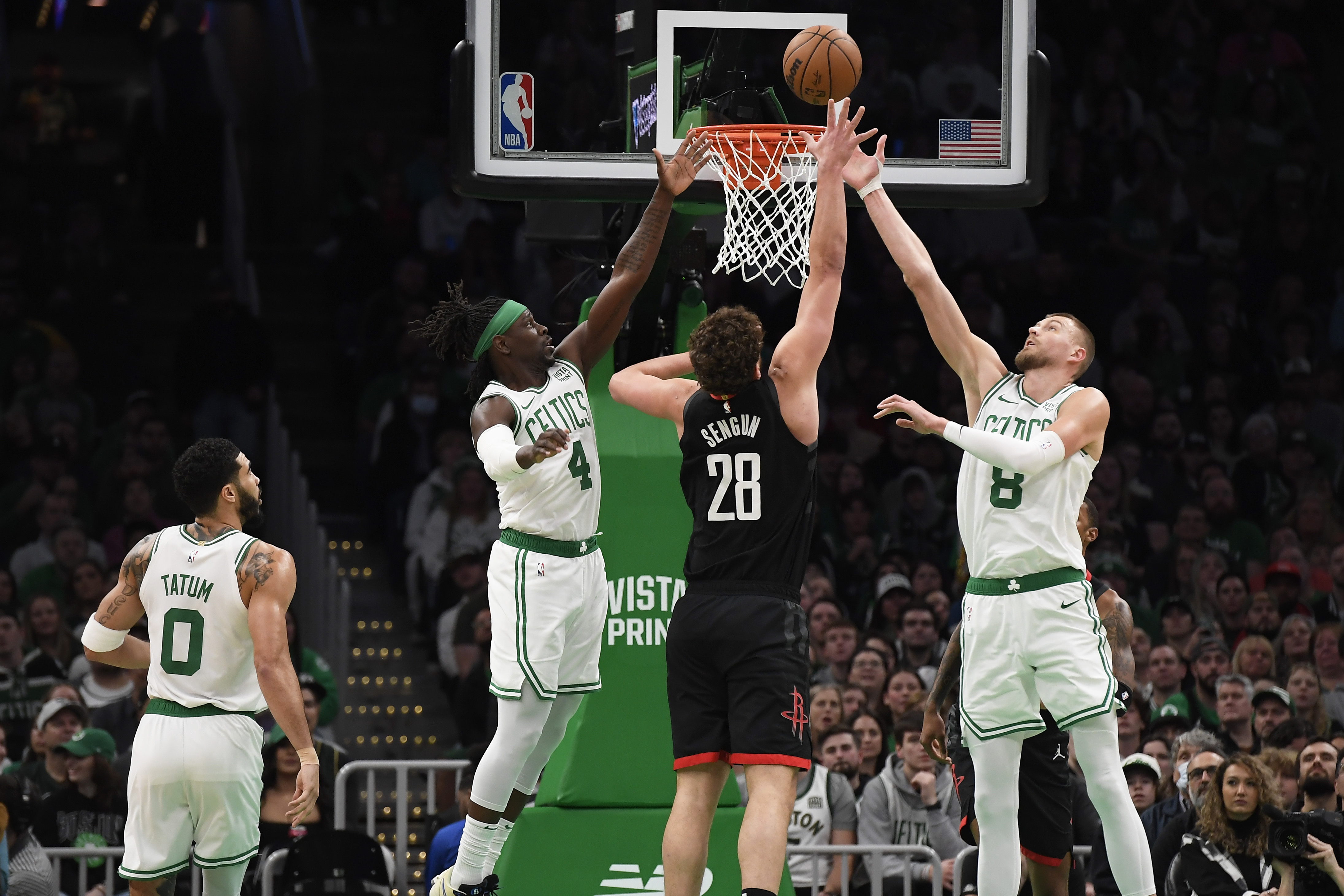 Boston Celtics guard Jrue Holiday (4) and center Kristaps Porzingis (8) and Houston Rockets center Alperen Sengun (28) battle for a rebound during the first half at TD Garden.