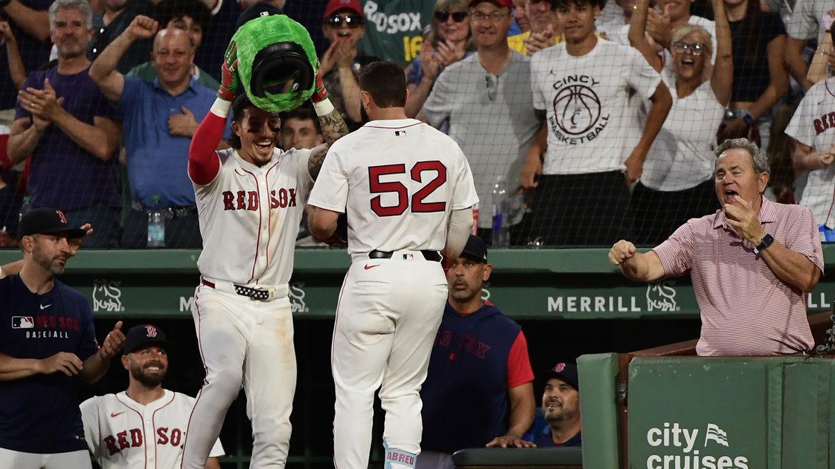 Boston Red Sox left fielder Jarren Duran (16) places the Wally helmet on right fielder Wilyer Abreu (52) after hitting an inside the park home run during the fifth inning against the Cincinnati Reds at Fenway Park.