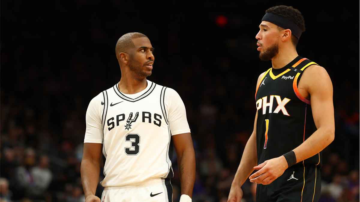 San Antonio Spurs guard Chris Paul (3) talks to Phoenix Suns guard Devin Booker (1) in the second half of an NBA Cup game at Footprint Center.