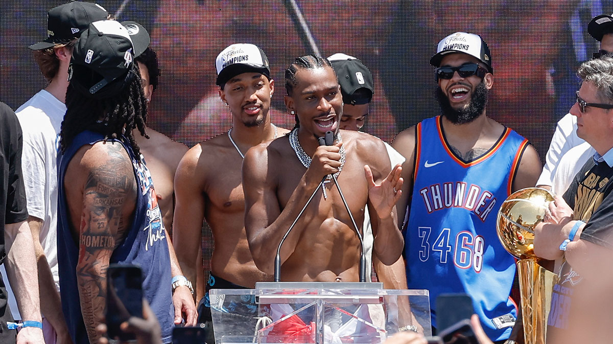 Thunder guard Shai Gilgeous-Alexander speaks to fans during the Oklahoma City Thunder Champions parade with the over/under in the background