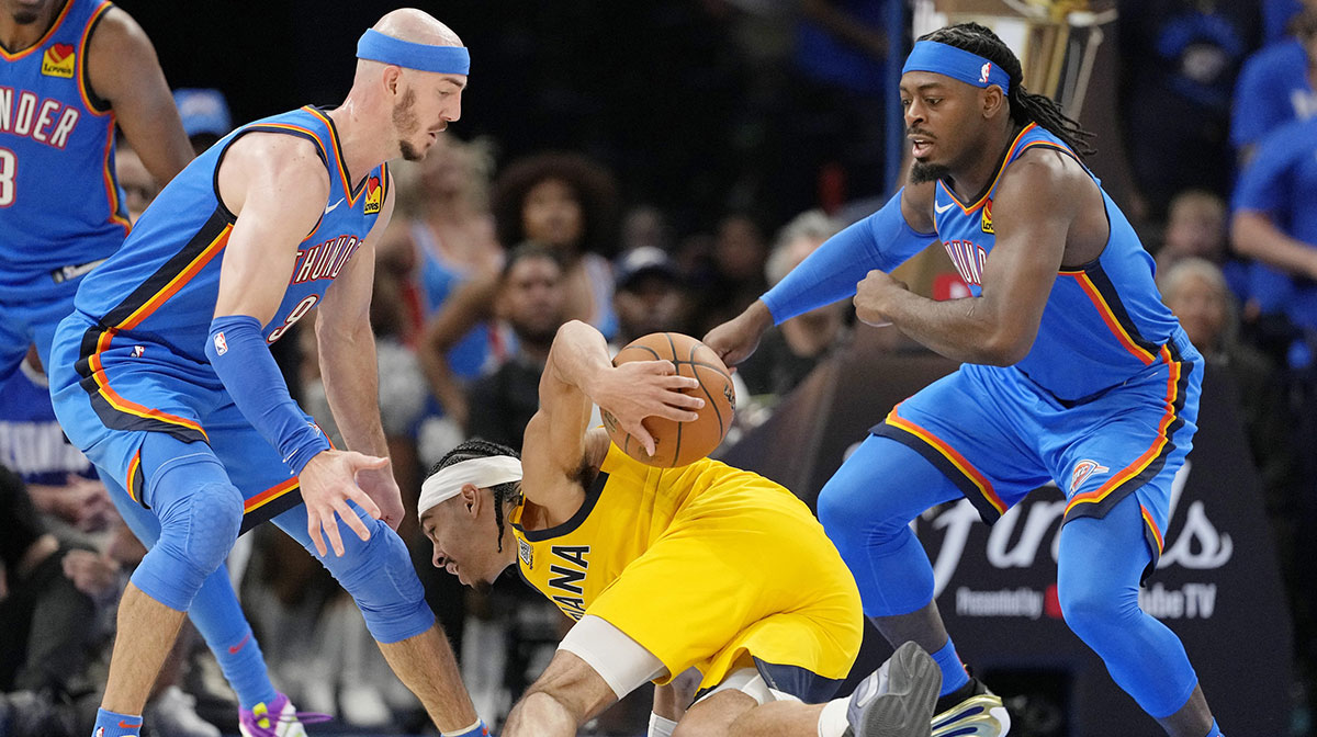 Indiana Pacers guard Andrew Nembhard (2) falls with the ball against Oklahoma City Thunder guard Alex Caruso (left) and guard Luguentz Dort (right) during the second half during game two of the 2025 NBA Finals at Paycom Center.