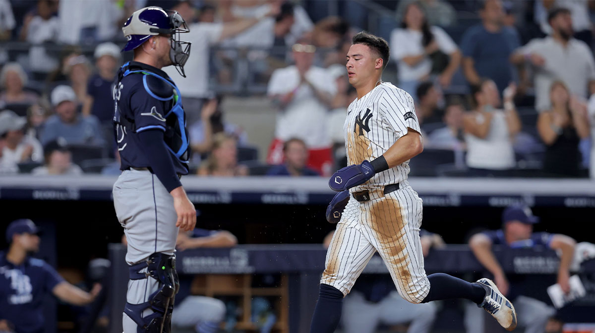 New York Yankees shortstop Anthony Volpe (11) scores a run after Tampa Bay Rays catcher Nick Fortes (40) threw the ball away when Volpe stole third base during the fourth inning at Yankee Stadium.