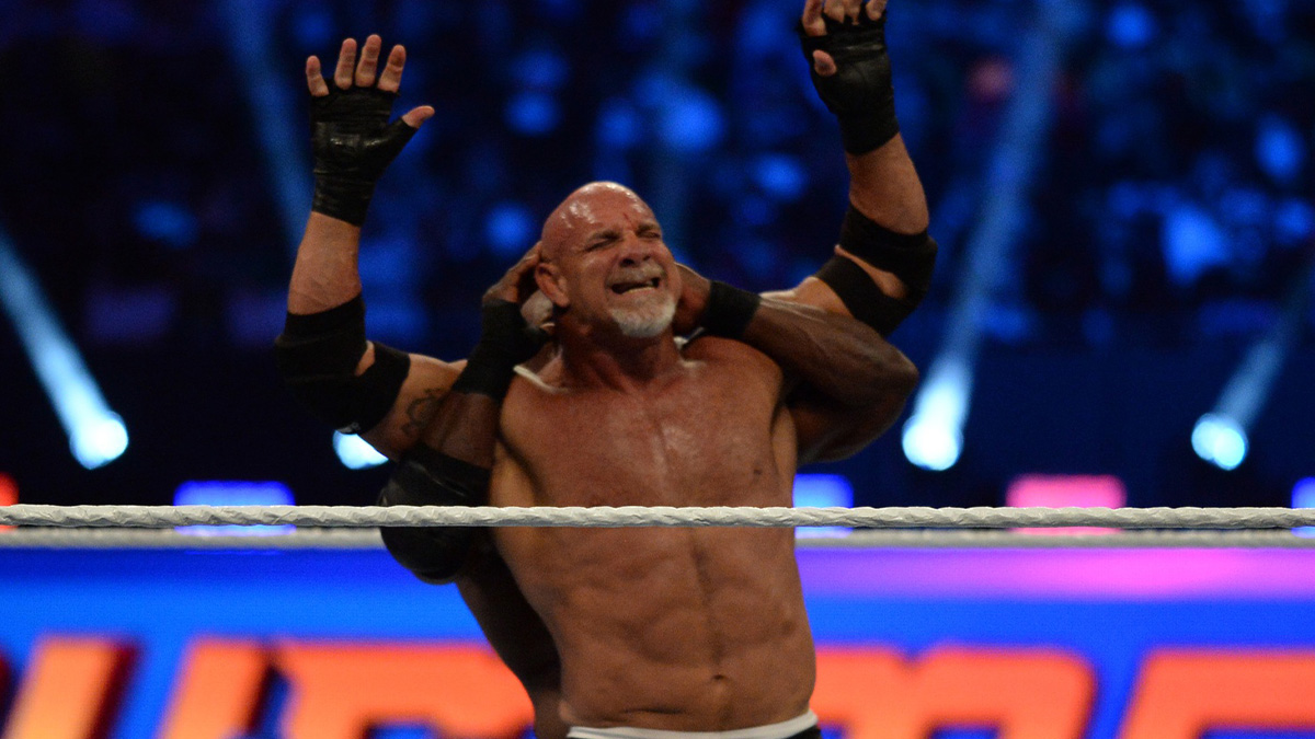 Goldberg (black trunks) with son Gage (street clothes) faces Bobby Lashley (black pants) with MVP (suit) for the WWE World Heavy Championship at SummerSlam 2021 at Allegiant Stadium.