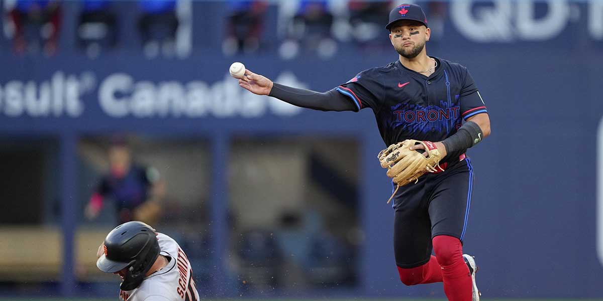 Toronto Blue Jays shortstop Bo Bichette (11) turns a double play against San Francisco Giants second baseman Casey Schmitt (10) and first baseman Dominic Smith (not pictured) during the second inning at Rogers Centre.