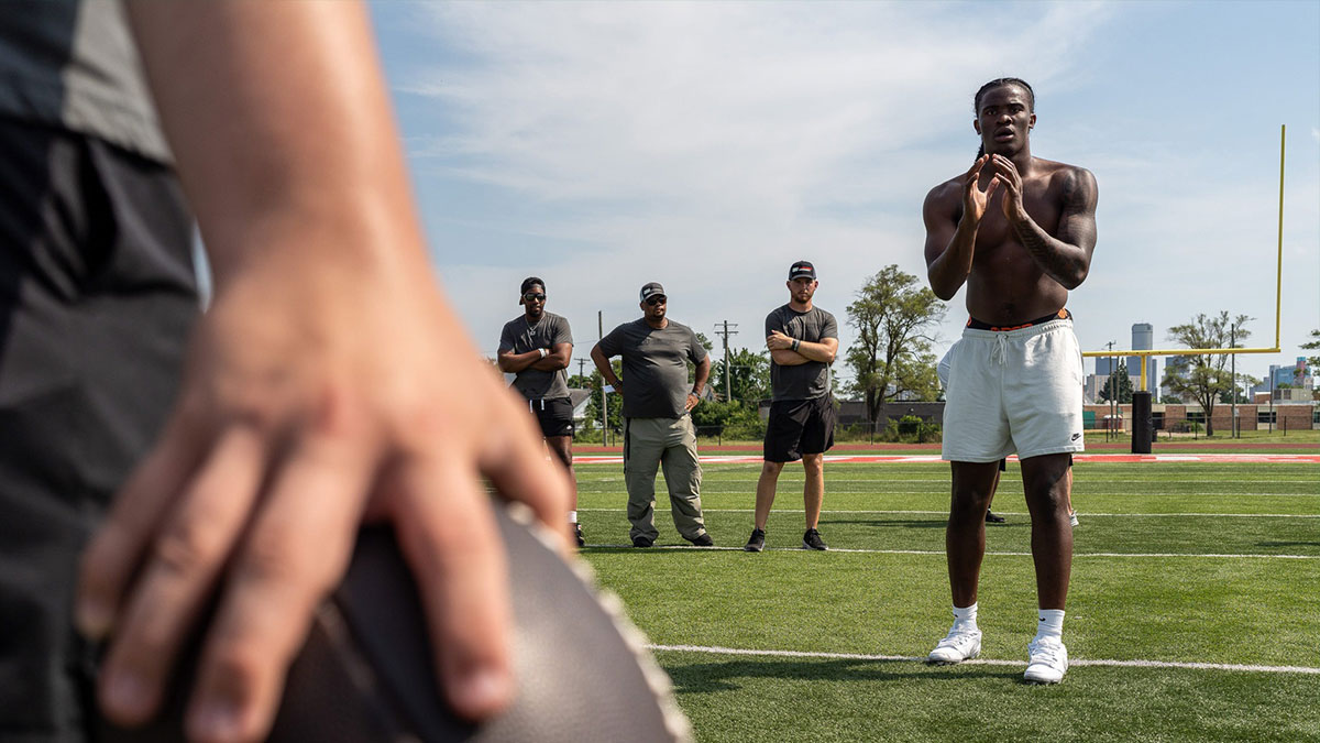 Josh Putman, 19, a member of Quarterback University, prepares to snap the ball to Bryce Underwood, 17, a freshman quarterback at the University of Michigan, during a private workout