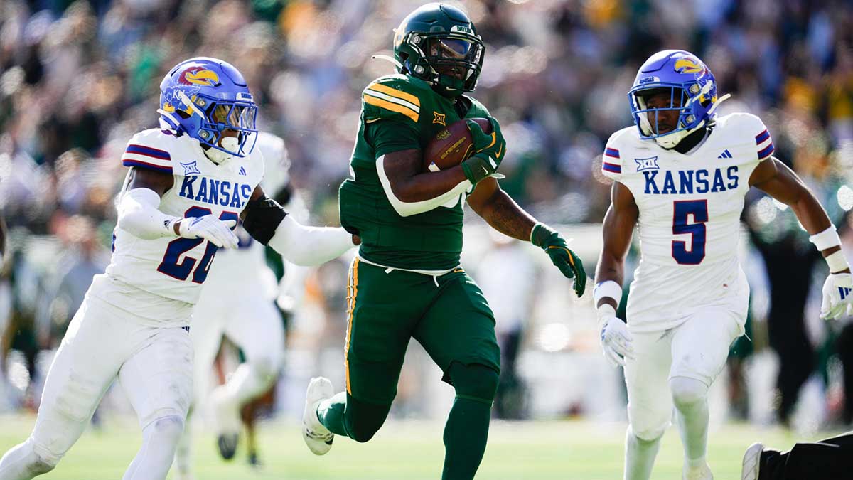  Baylor Bears running back Bryson Washington (30) runs the ball for 50 yards while being chased by Kansas Jayhawks cornerback Jalen Todd (26) and safety O.J. Burroughs (5) during the first half at McLane Stadium.