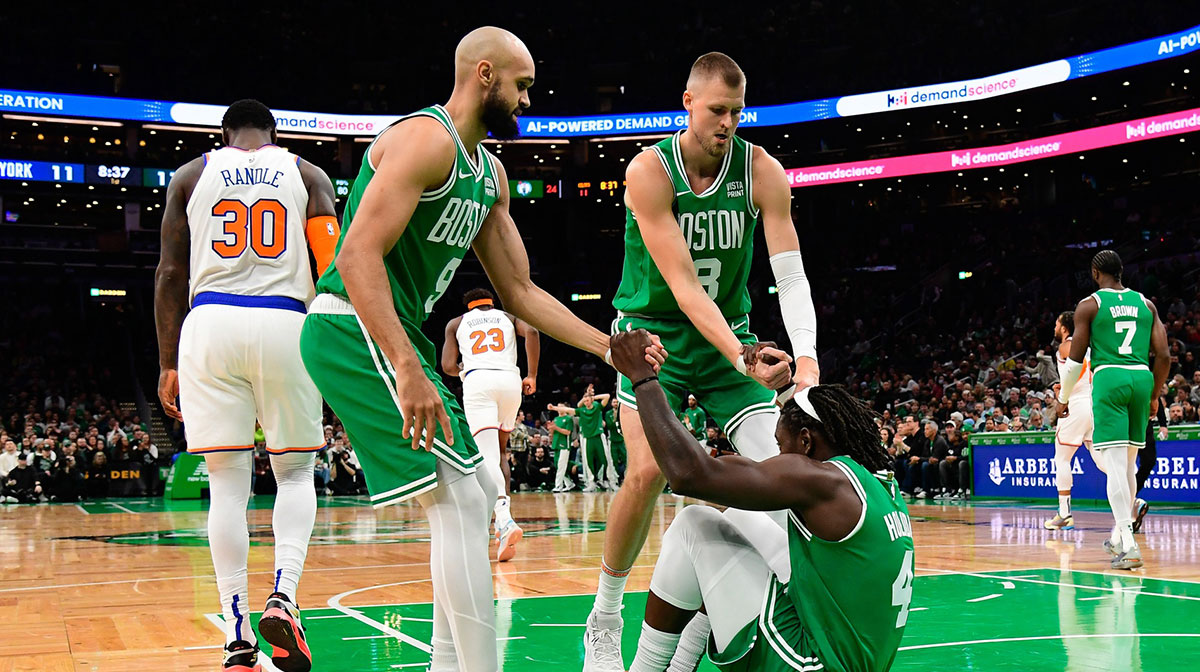 Boston Celtics guard Jrue Holiday (4) is helped to his feet by guard Derrick White (9) and center Kristaps Porzingis (8) during the first half against the New York Knicks at TD Garden.