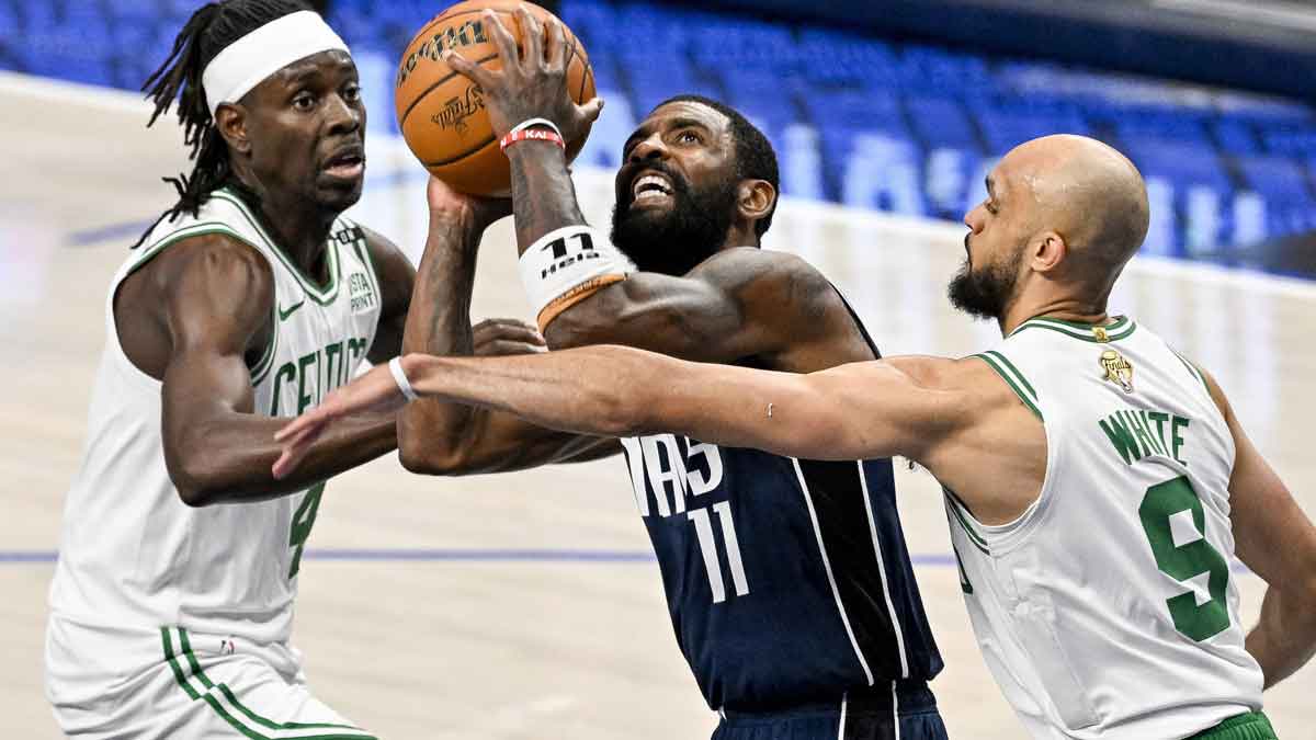 Dallas Mavericks guard Kyrie Irving (11) drives to the basket between Boston Celtics guard Jrue Holiday (4) and guard Derrick White (9) during the game between the Dallas Mavericks and the Boston Celtics in game four of the 2024 NBA Finals at American Airlines Center.