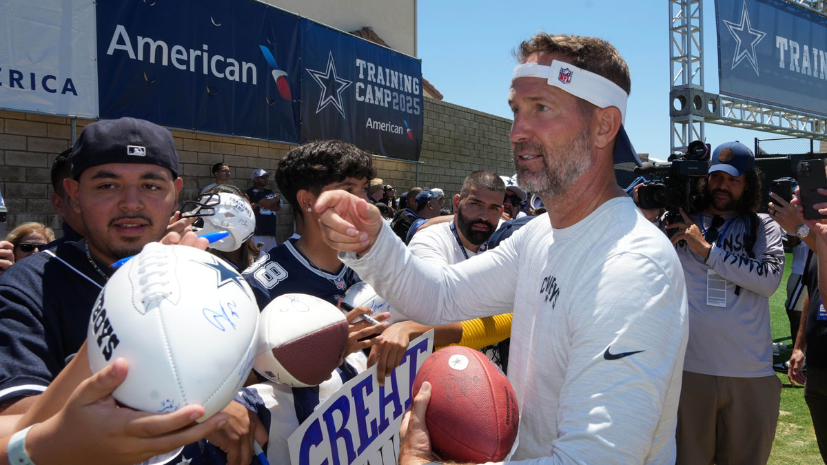 Dallas Cowboys coach Brian Schottenheimer signs autographs at training camp at the River Ridge Fields. 
