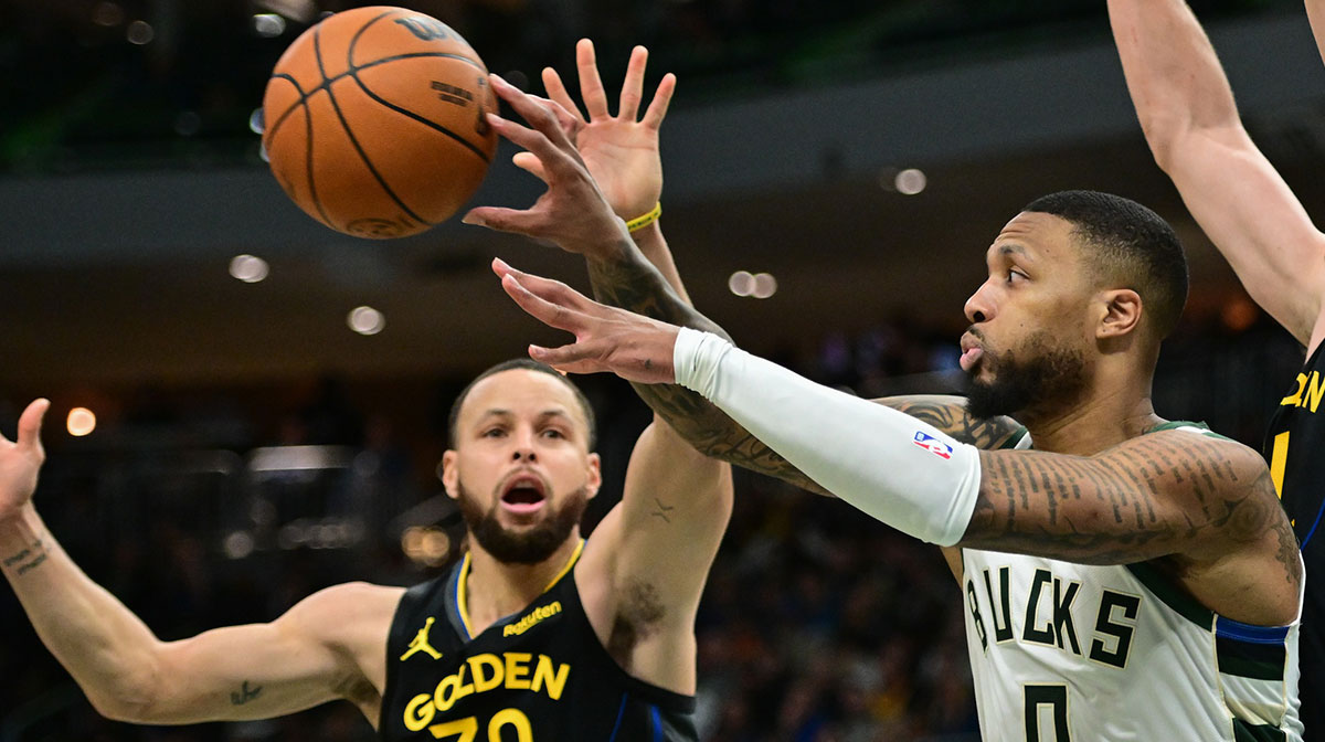 Milwaukee Bucks guard Damian Lillard (0) passes the ball away from Golden State Warriors guard Stephen Curry (30) in the fourth quarter at Fiserv Forum.