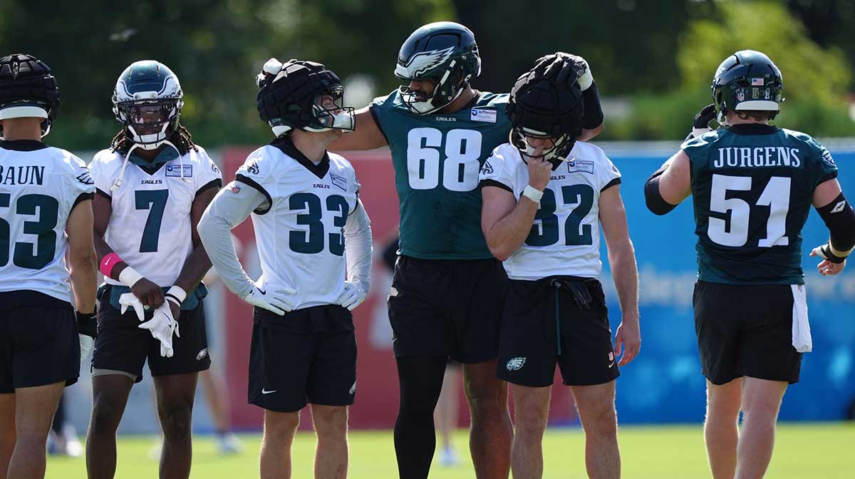Eagles offensive lineman Jordan Mailata (68) reacts with defensive back Cooper DeJean (33) and safety Reed Blankenship during training camp at NovaCare Complex