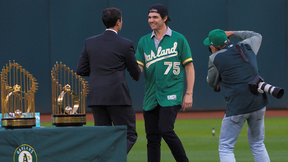 Oakland Athletics president Dave Kaval shakes hands with former player Barry Zito (middle) during a presentation to recognize the 50th anniversary team at Oakland Coliseum.