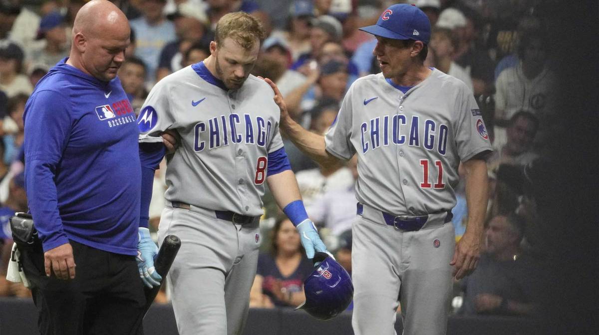Chicago Cubs outfielder Ian Happ (8) is helped off the field by a Chicago Cubs trainer and manager Craig Counsell (11) after fouling a ball off his foot against the Milwaukee Brewers in the eighth inning at American Family Field.