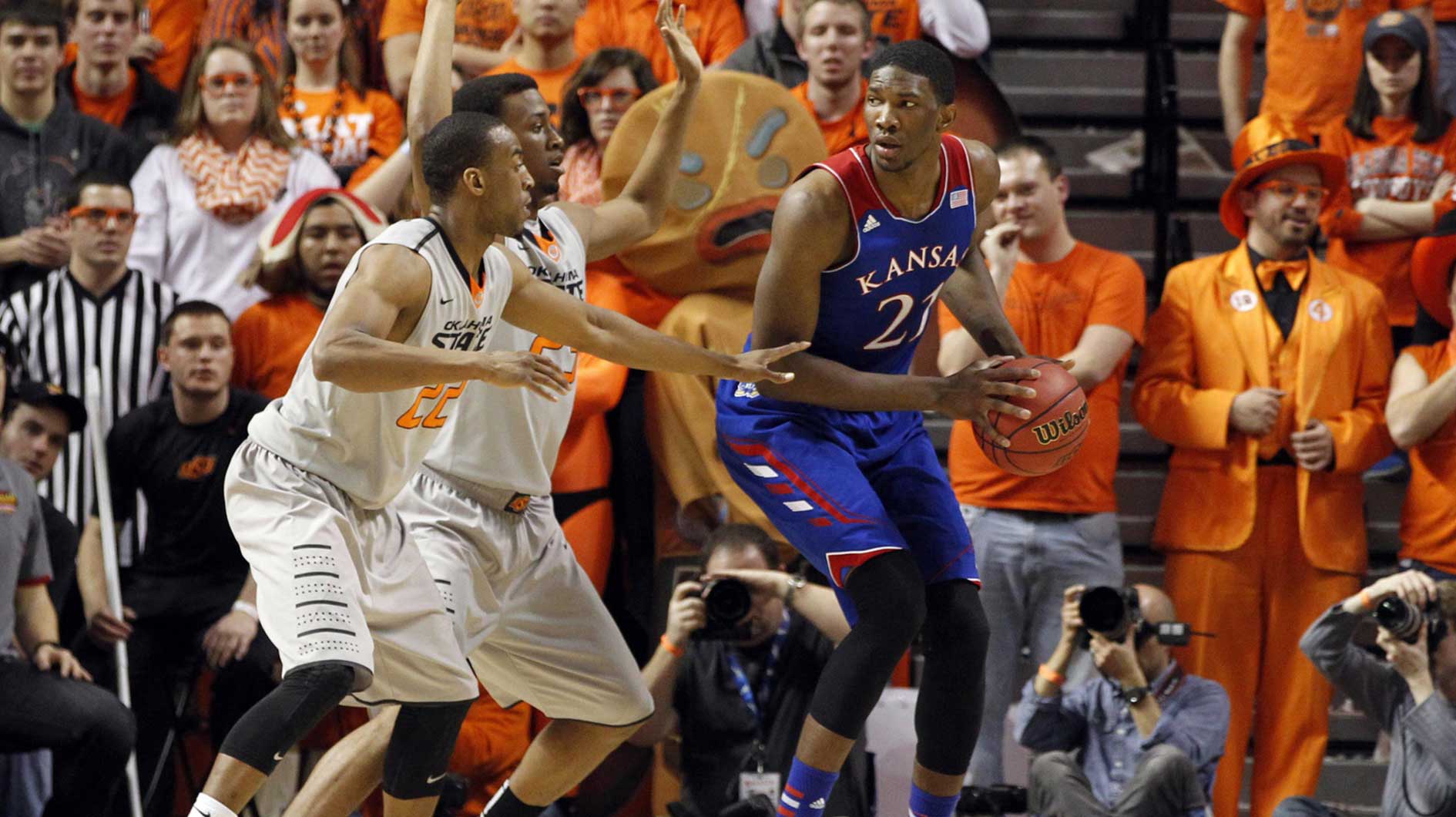 Kansas Jayhawks center Joel Embiid (21) is defended by Oklahoma State Cowboys forward/center Kamari Murphy (21) and guard Markel Brown (22) during the first half at Gallagher-Iba Arena.