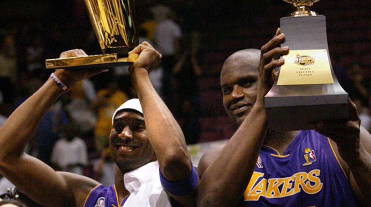 The Lakers Kobe Bryant holds up the Championship trophy along with teammate Shaquille O'Neal who holds up his third MVP trophy.