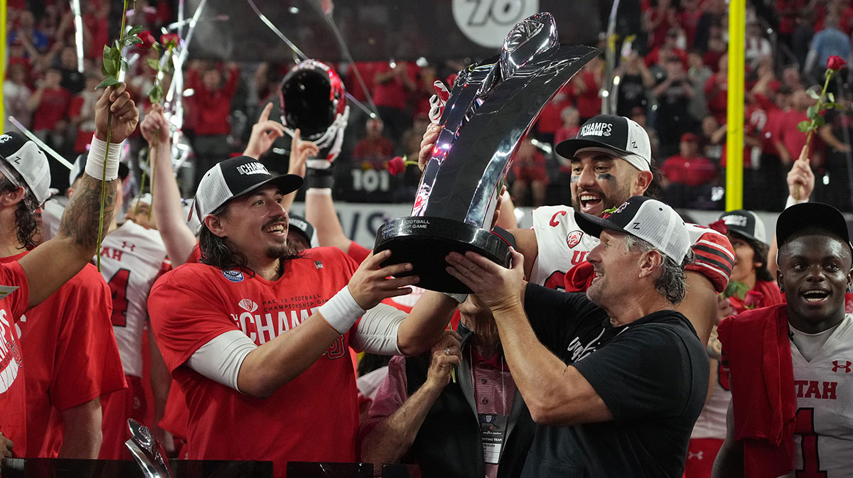 Utah Utes quarterback Cameron Rising (left) and coach Kyle Whittingham hoist the Pac-12 Championship trophy after the game against the Southern California Trojans at Allegiant Stadium.