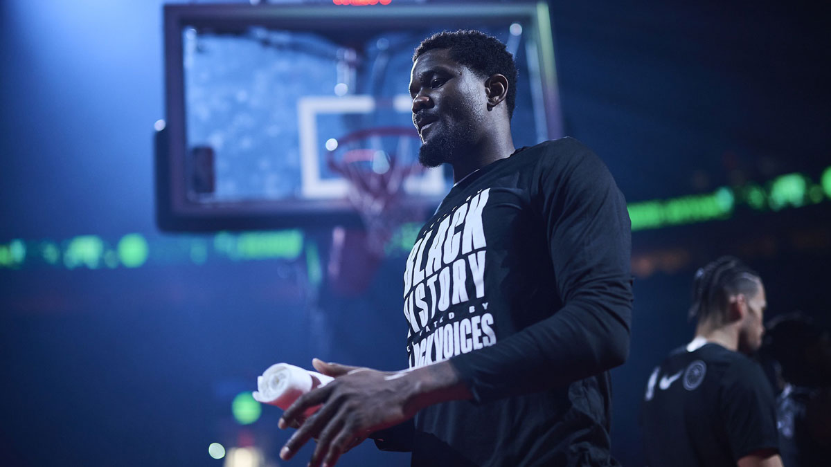 Blazers center Deandre Ayton (2) walks out to the court during introductions before a game against the Sacramento Kings at Moda Center with the Suns logo in the background