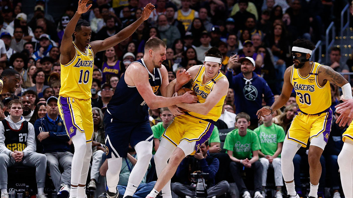Lakers guard Austin Reaves (15) steals the ball away from Denver Nuggets center Nikola Jokic (15) as center Christian Koloko (10) and guard Jordan Goodwin (30) defend in the fourth quarter at Ball Arena with Lakers' Marcus Smart in the background and Lakers deal