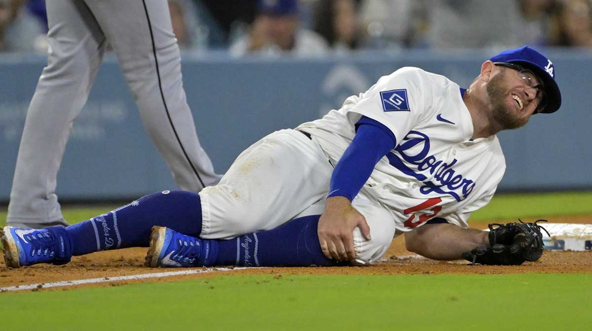 Los Angeles Dodgers third baseman Max Muncy (13) grabs his knee after tagging Chicago White Sox right fielder Michael A. Taylor (21) out on an attempted stolen base during the fifth inning at Dodger Stadium.
