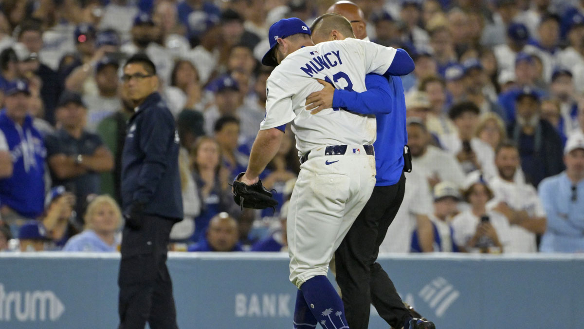 Los Angeles Dodgers third baseman Max Muncy (13) is helped off the field after he was injured on a play during the fifth inning against the Chicago White Sox at Dodger Stadium.